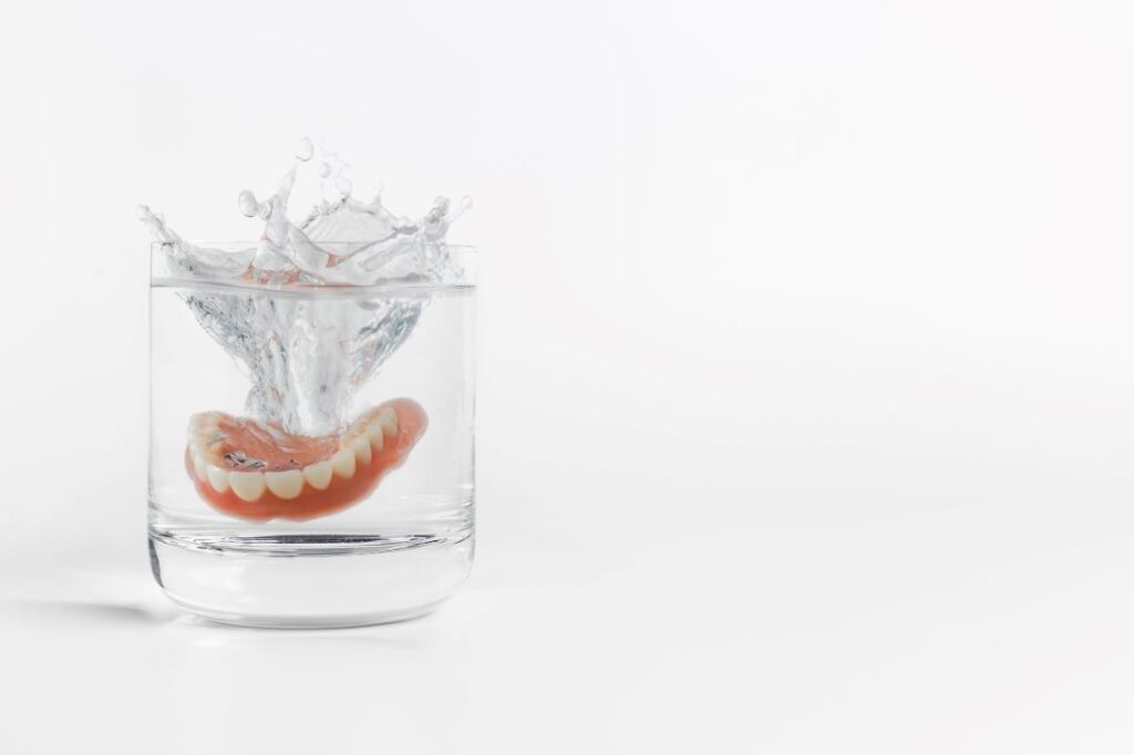 A denture soaking in a glass of water.