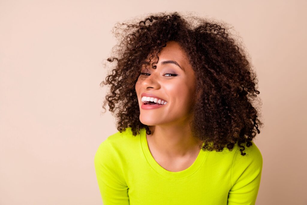 Woman in a chartreuse shirt smiling with tan background